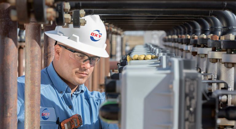 Man wearing helmet checking metres at an gas refinery