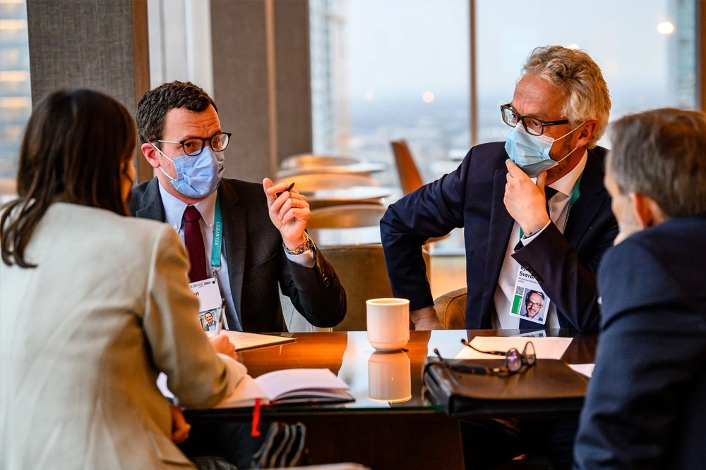 Two men wearing face masks having a meeting with two other people during COVID