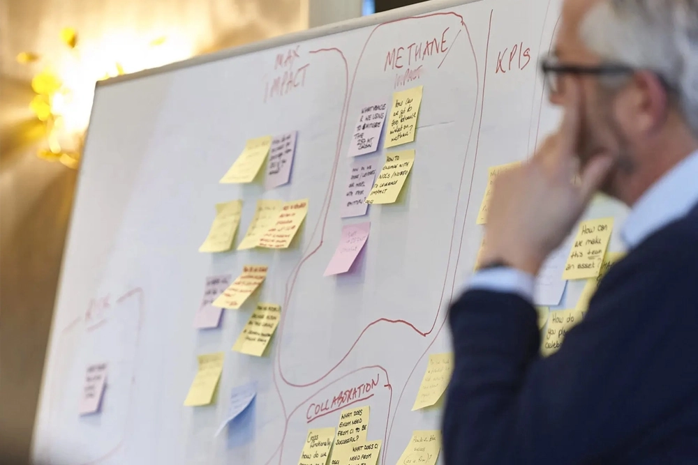 Man thoughtfully looking at a whiteboard with sticky notes attached