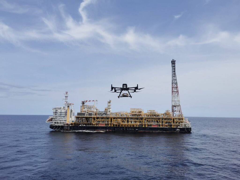 An offshore oil rig with a drone flying in front of it.
