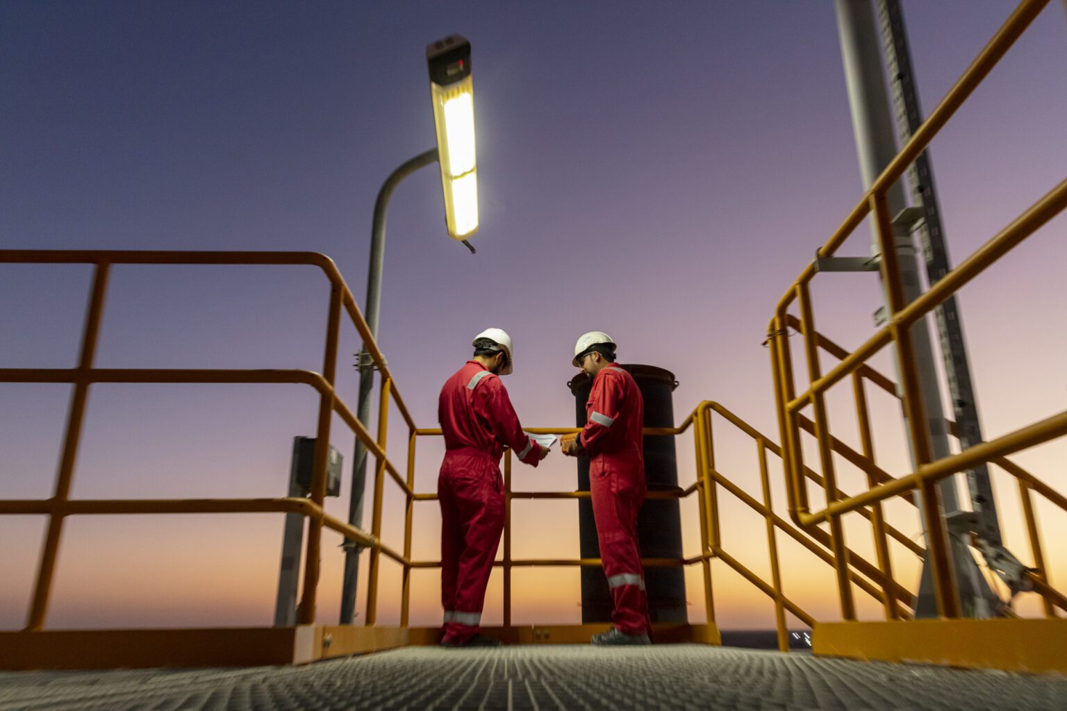 Two engineers working at dusk at Block 61 Gas Field in Oman