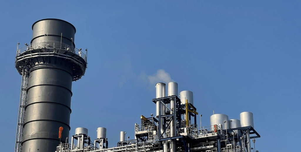 Metal chimneys protruding into the sky from an oil field.