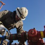 An Oilfield Worker in His Thirties Pumps Down Lines at an Oil and Gas Drilling Pad Site on a Cold, Sunny, Winter Morning