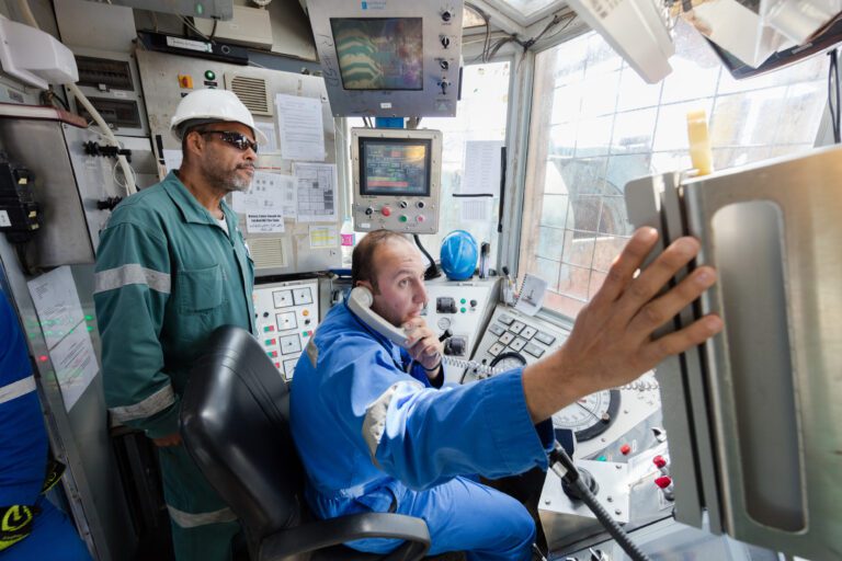 Two male employees working int he control room of Mocha-1 onshore drill rig.