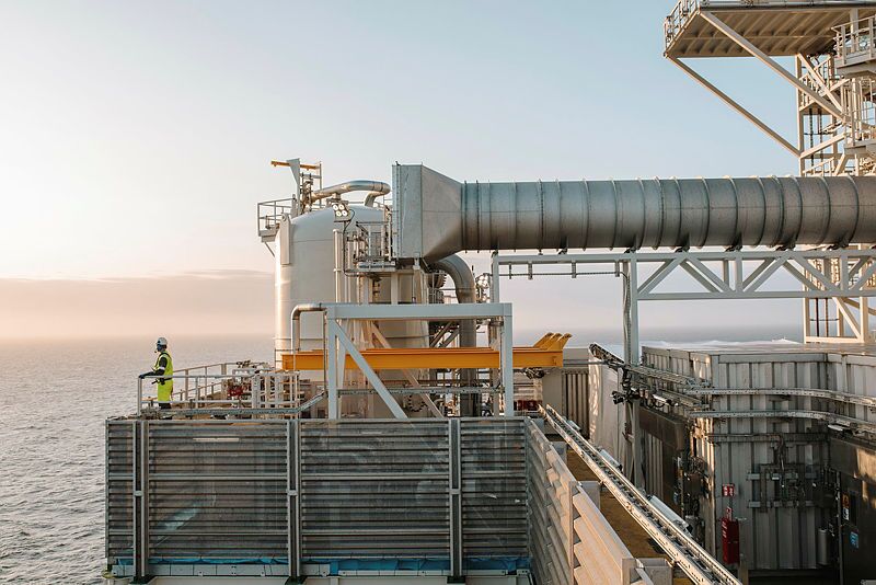 A worker looking out over the sea from the edge of an oil rig.