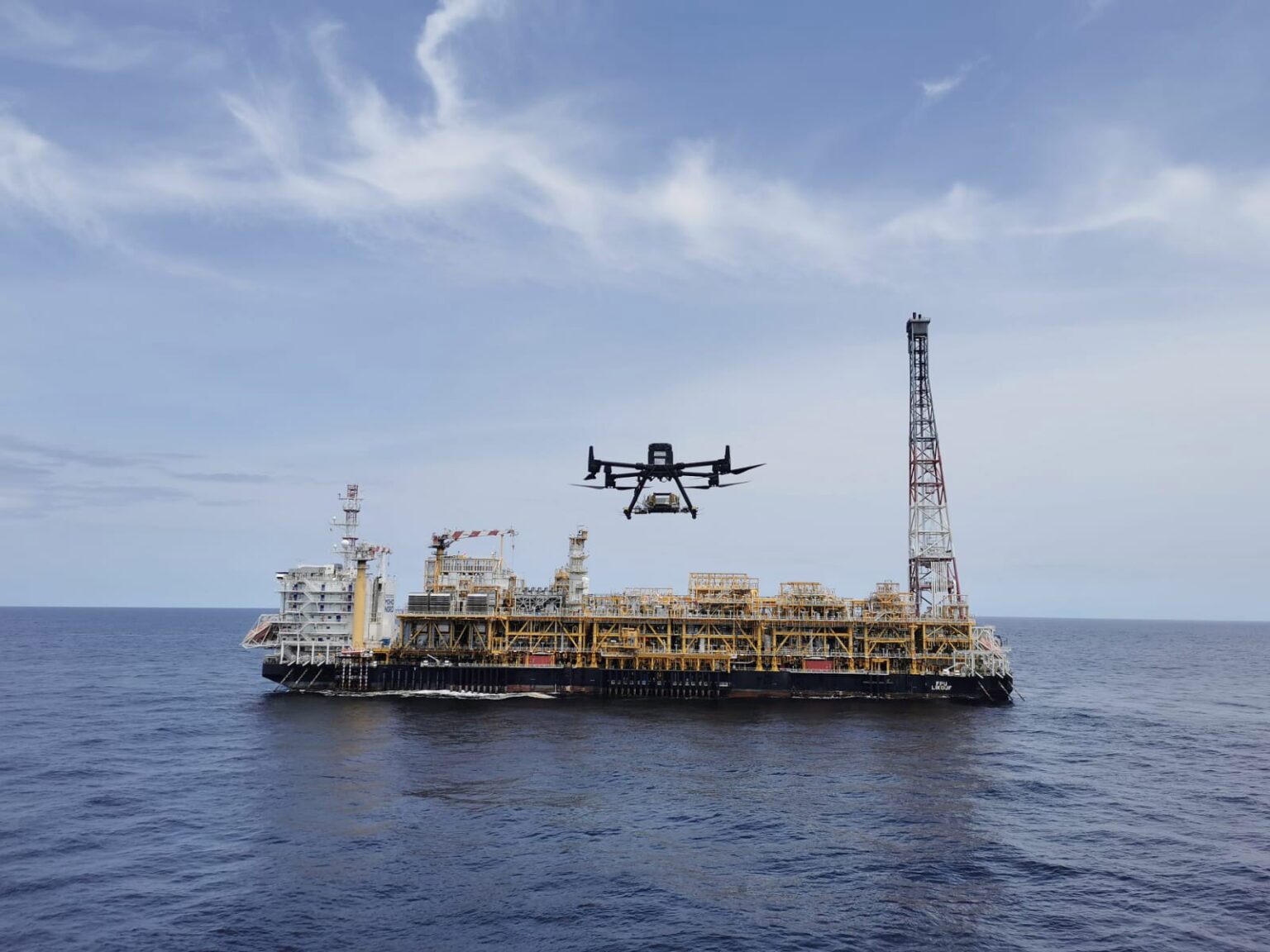 An offshore oil rig with a drone flying in front of it.