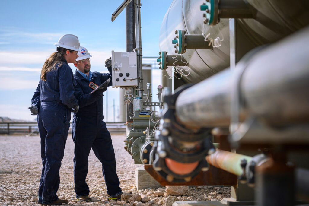 Two Oxy engineers, one male and one female, working on an oil field.