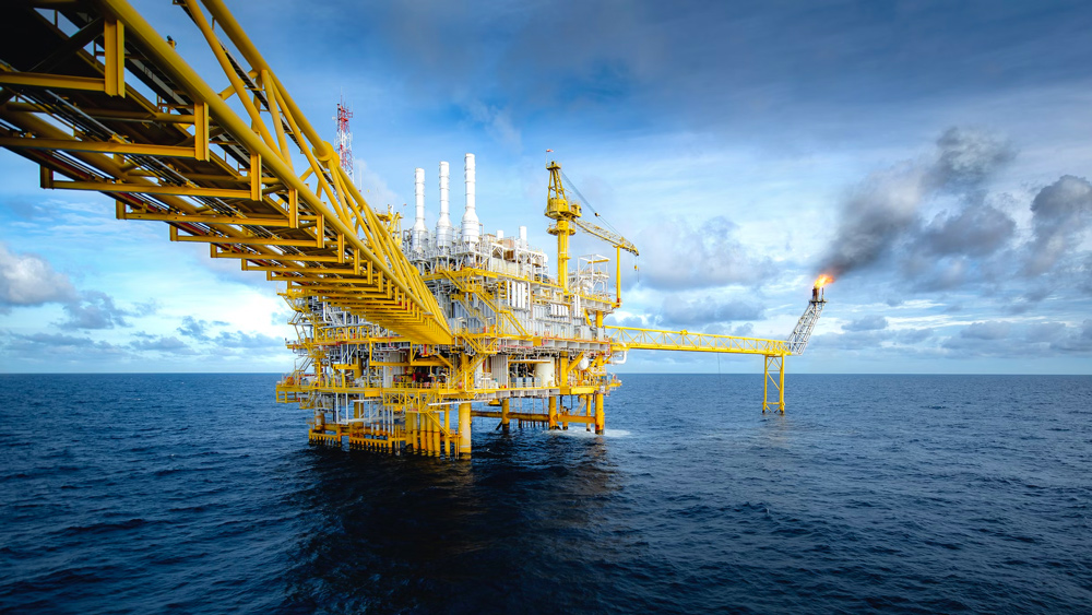 A predominantly yellow oil rig in the ocean.