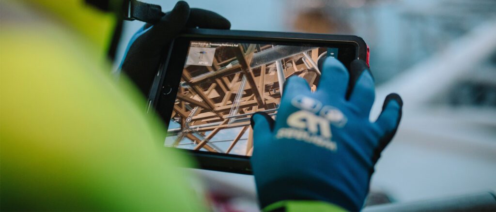 Close up of a gloved hand working on a handheld digital device.